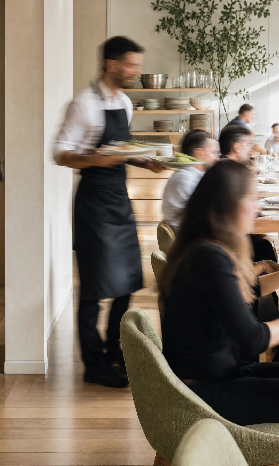 Restaurante com o salão cheio e um garçom levando pratos entre as mesas